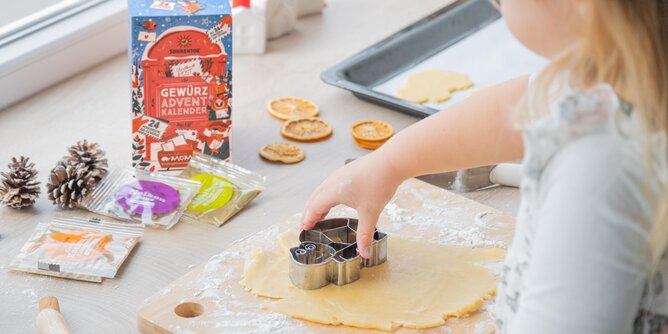 Ein Kind backt Schildkrötenkekse, daneben steht ein SONNENTOR Gewürzadventkalender | © SONNENTOR